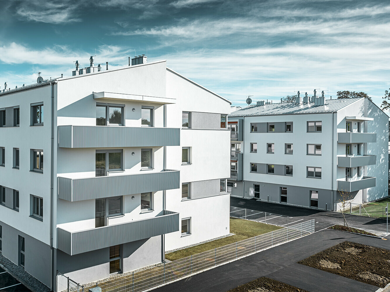 Modern apartment complex with a white façade and balconies with a PREFA serrated profile in metallic silver