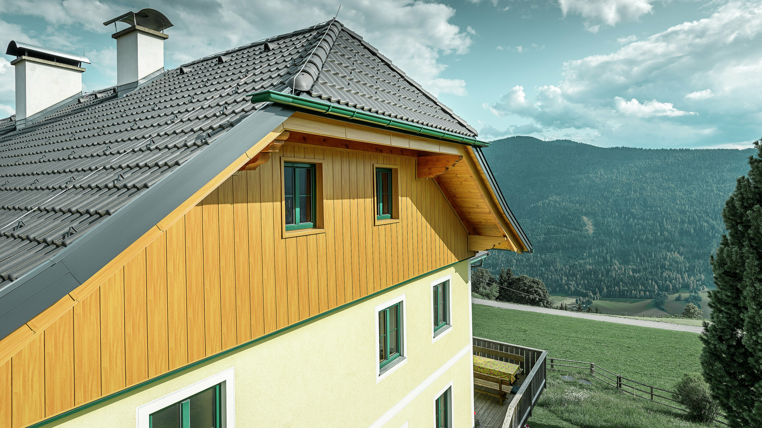 Detailansicht der Giebelverkleidung mit PREFA Sidings in Eiche natur an einem Wohnhaus in Ranten mit Blick auf die umliegende Berglandschaft.