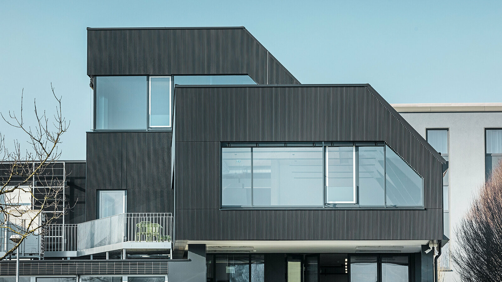 Side view of the Amann café on a sunny day. A corrugated profile in black was used to protect the building.