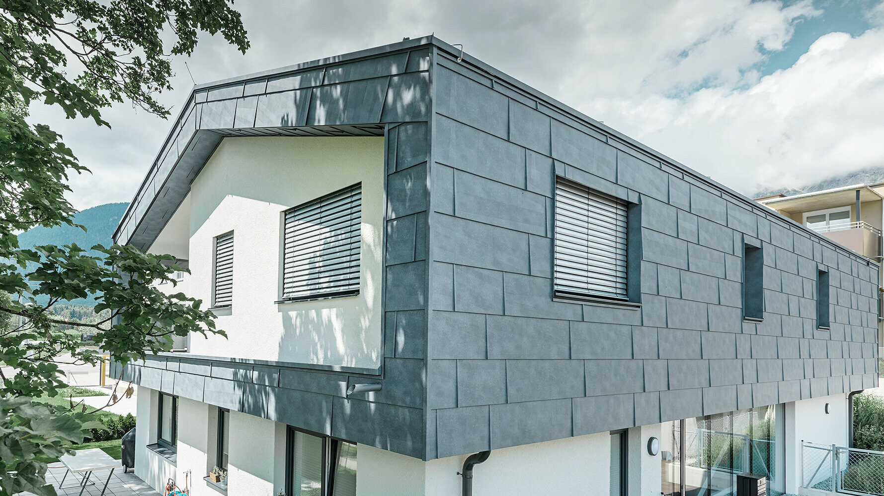 Modern detached house without eaves; the upper floor was  clad with PREFA FX.12 façade panels in stone grey, the rest of the façade was plastered white.