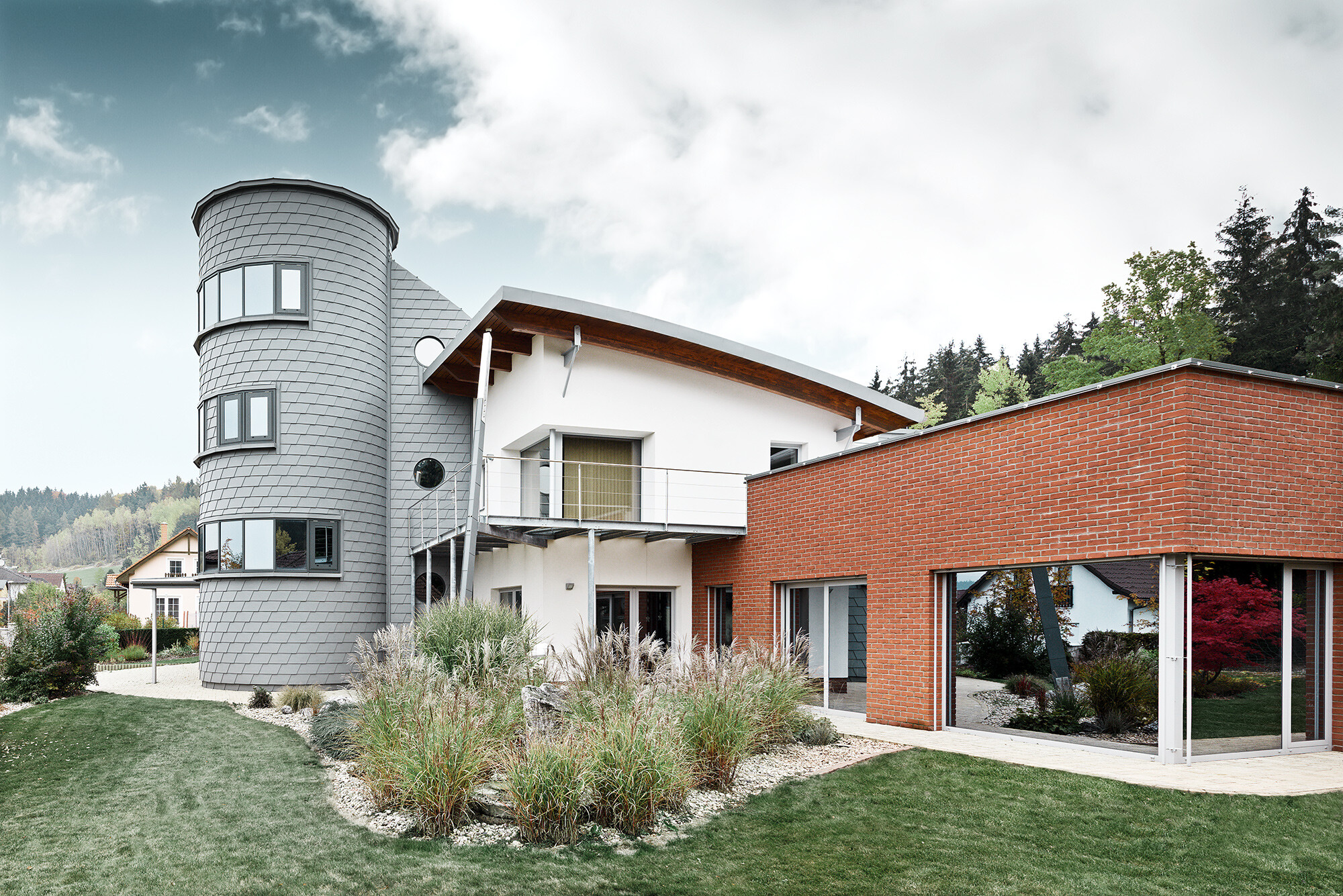 Detached house with tower extension, the round tower is clad with PREFA façade shingles in patina grey 