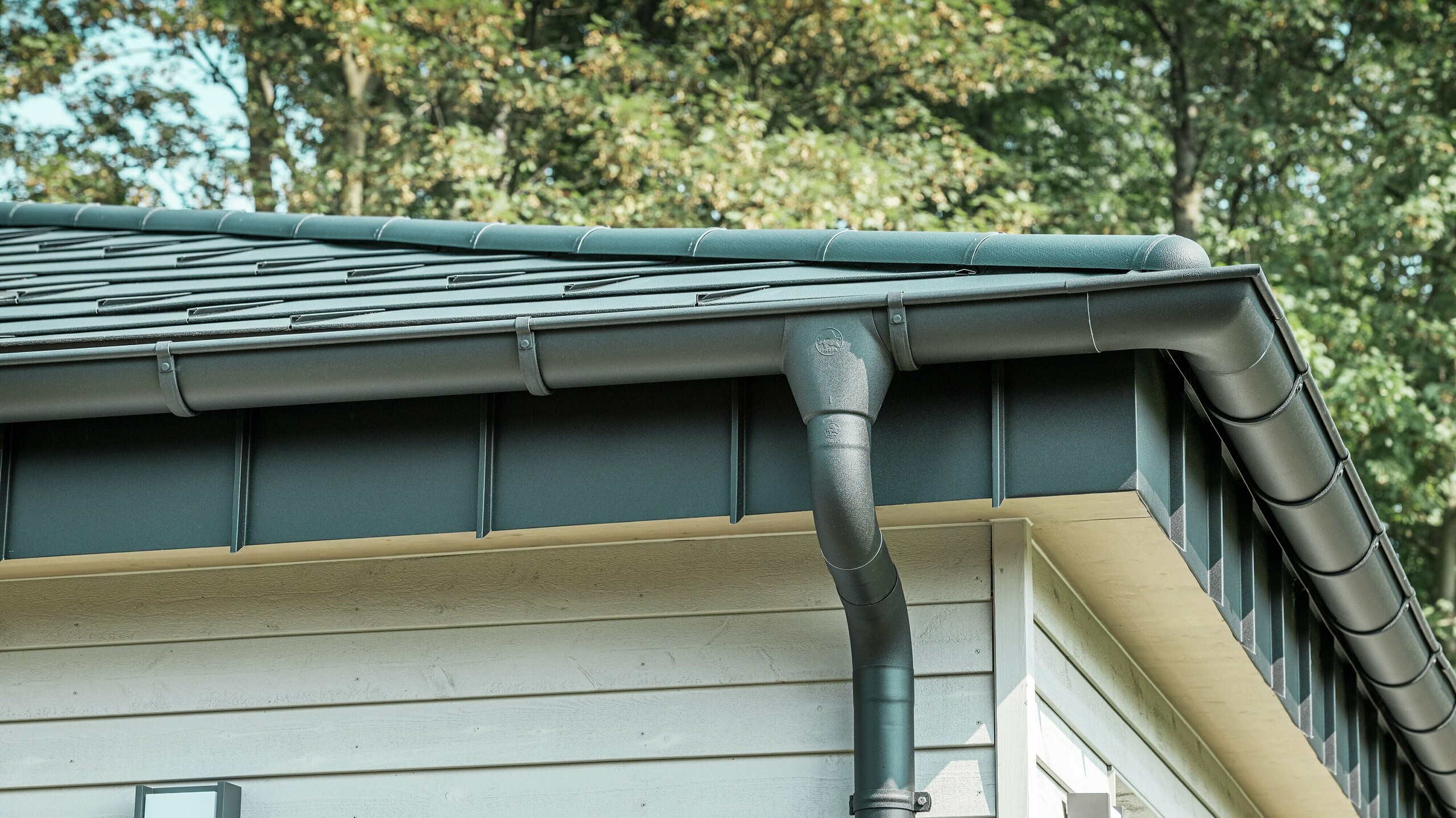 Detailed view of PREFA roof drainage on a bungalow in Rommerskirchen. The high-quality on-roof gutter and downpipe in P.10 black ensure reliable roof drainage when it rains. The durable PREFA aluminium products combine functionality with modern, elegant design.