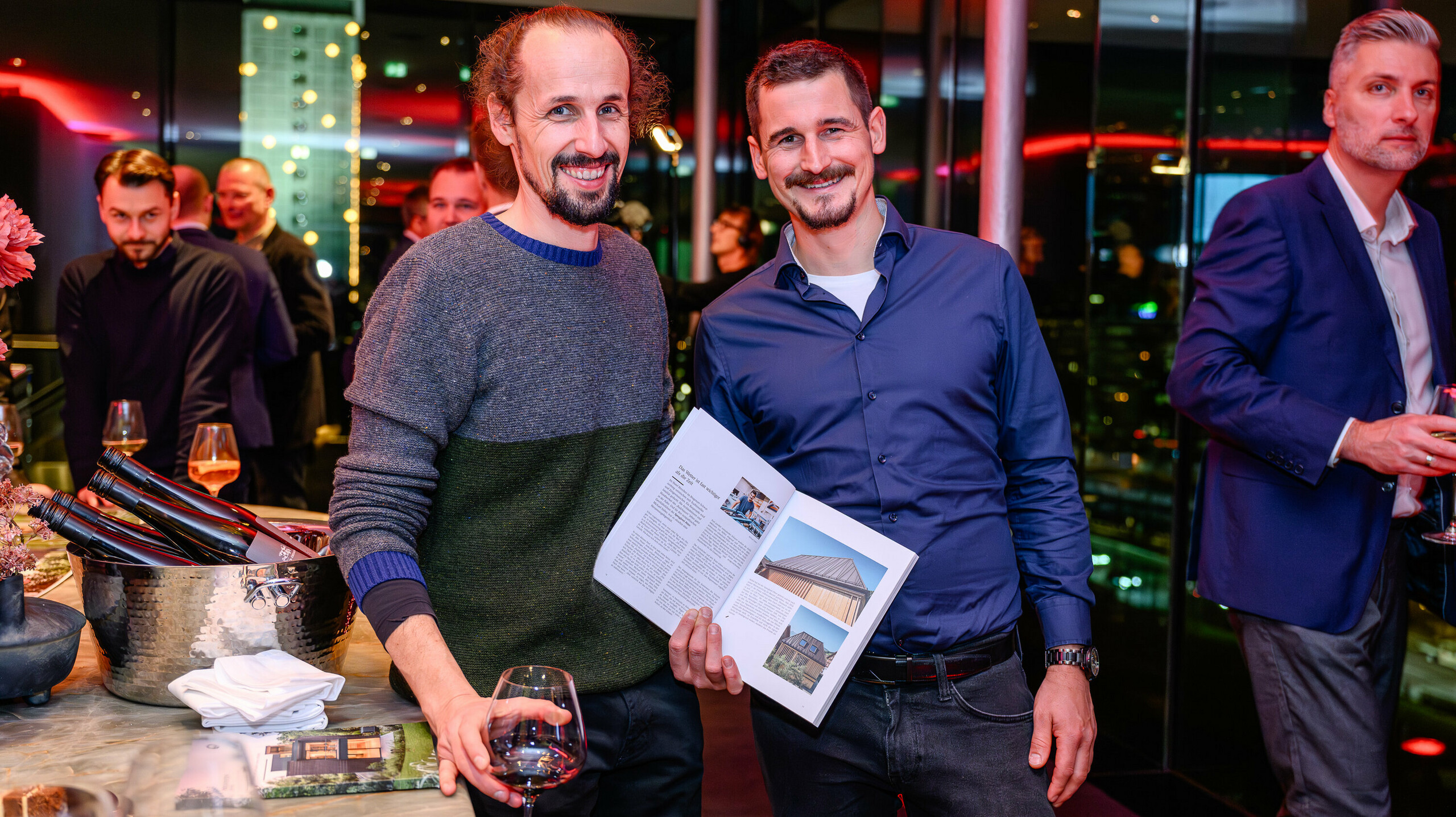 Strahlende Gesichter bei der PREFARENZEN Präsentation 2026: Zwei Projektbeteiligte präsentieren stolz ihr veröffentlichtes Objekt im neuen PREFA Architekturbuch. Die abgebildete Villa kombiniert natürliche Holzoptik mit PREFALZ – ein Paradebeispiel für modernen Materialkontrast und langlebige Ästhetik. Das Event im k47.wien verbindet Design, Architektur und Networking auf höchstem Niveau. PREFA Aluminiumprodukte zeigen hier ihre volle Stärke: witterungsbeständig, kreativ einsetzbar und stilbildend für zukunftsweisende Bauprojekte. Ein Abend voller Stolz, Austausch und Innovation.
