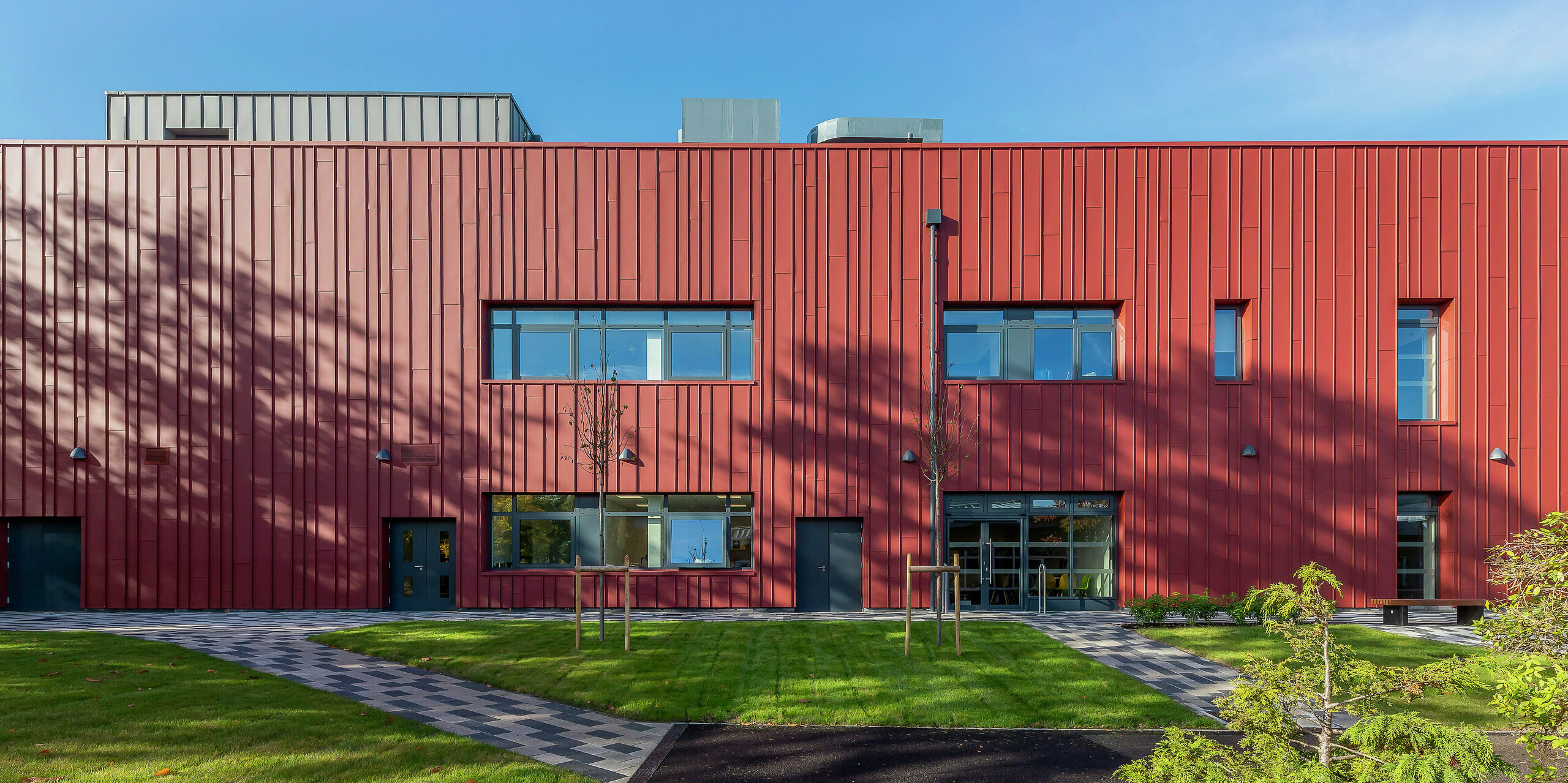 Modern façade design with PREFALZ: the Soldiers' Centre in Pirbright impresses with its high-quality standing seam cladding made of PREFALZ in P.10 oxide red. The stylish combination with window cladding in P.10 anthracite gives the army's social centre a striking appearance. This is where functionality and design come together – a sustainable architectural concept with durable aluminium.