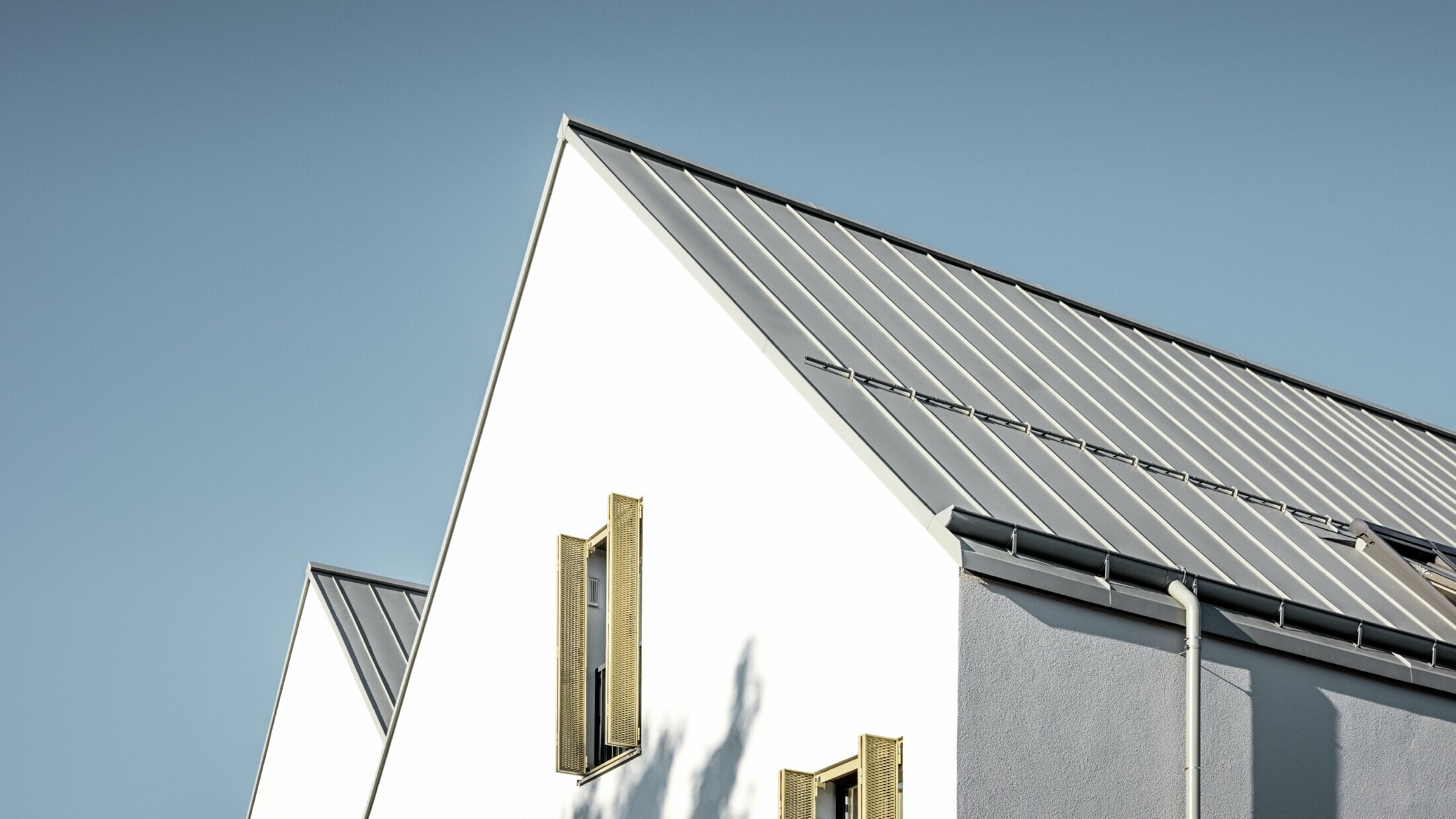 Gable roof without eaves, covered with PREFALZ standing seam in P.10 zinc grey with PREFA on-roof gutter