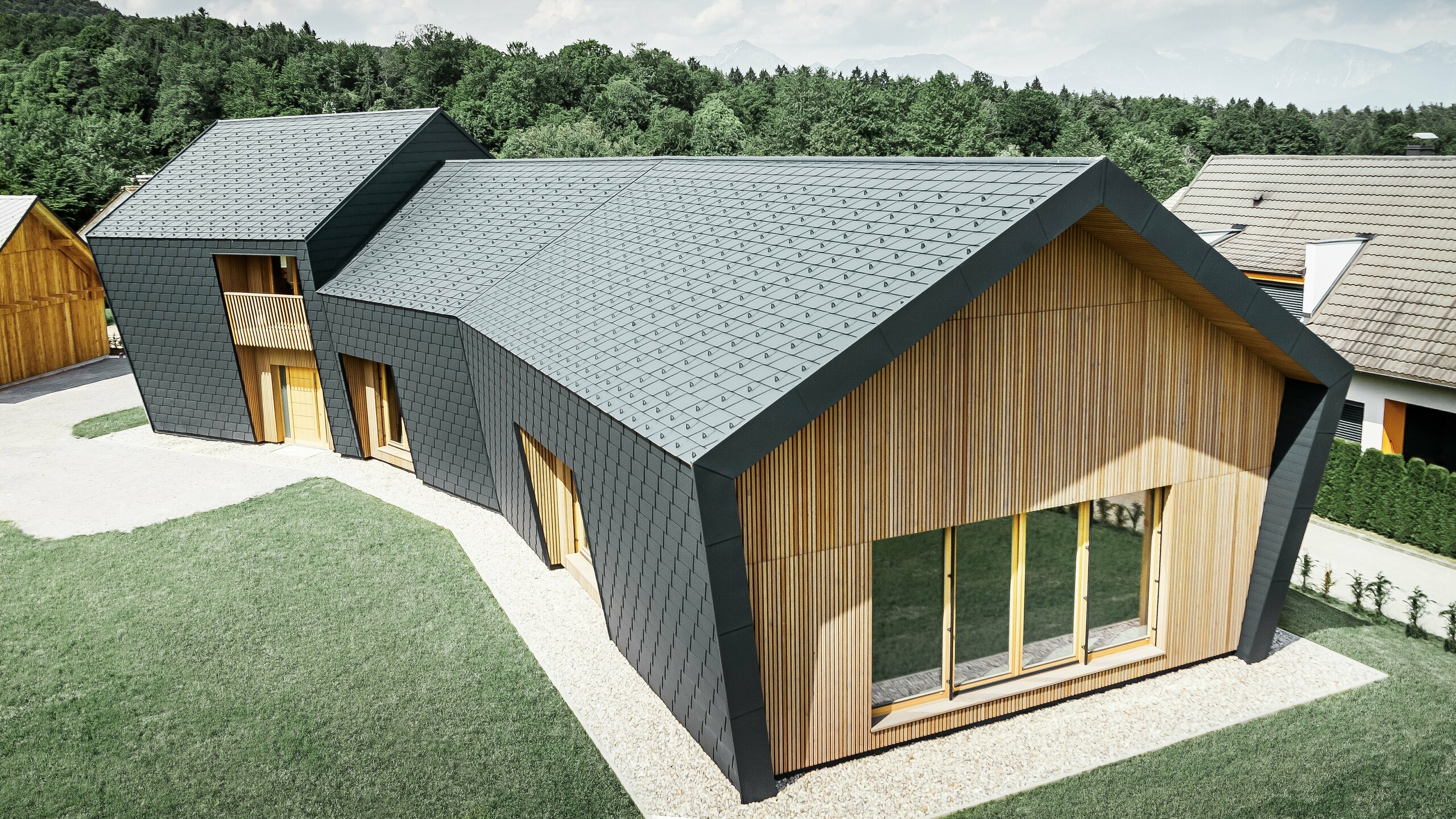 Large roof and façade areas, covered with DS.19 roof shingles in P.10 anthracite, on the front side the façade was clad with wood