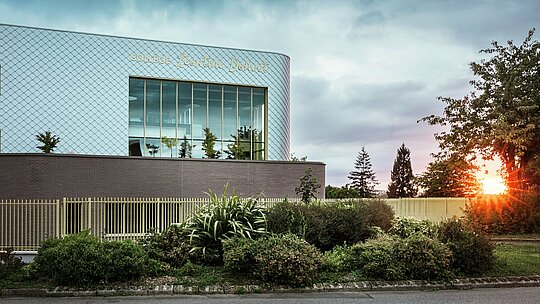 Das moderne Schulgebäude des Collège Léontine Dolivet in Cesson-Sévigné besticht durch seine markante Aluminiumfassade aus rund 15.000 PREFA-Wandelementen in Silbermetallic. Die glänzende Oberfläche reflektiert das Licht und verleiht dem Gebäude eine lebendige, elegante Ausstrahlung. Große Glasflächen eröffnen den Blick ins Grüne, während die robuste PREFA-Fassadenlösung Langlebigkeit und Witterungsbeständigkeit garantiert. Die Kombination aus wandelbarem Metall und klarer Architektur macht das Gebäude zu einem echten Blickfang und unterstreicht die Vorteile von Aluminium: geringes Gewicht, Wartungsfreiheit und Nachhaltigkeit.