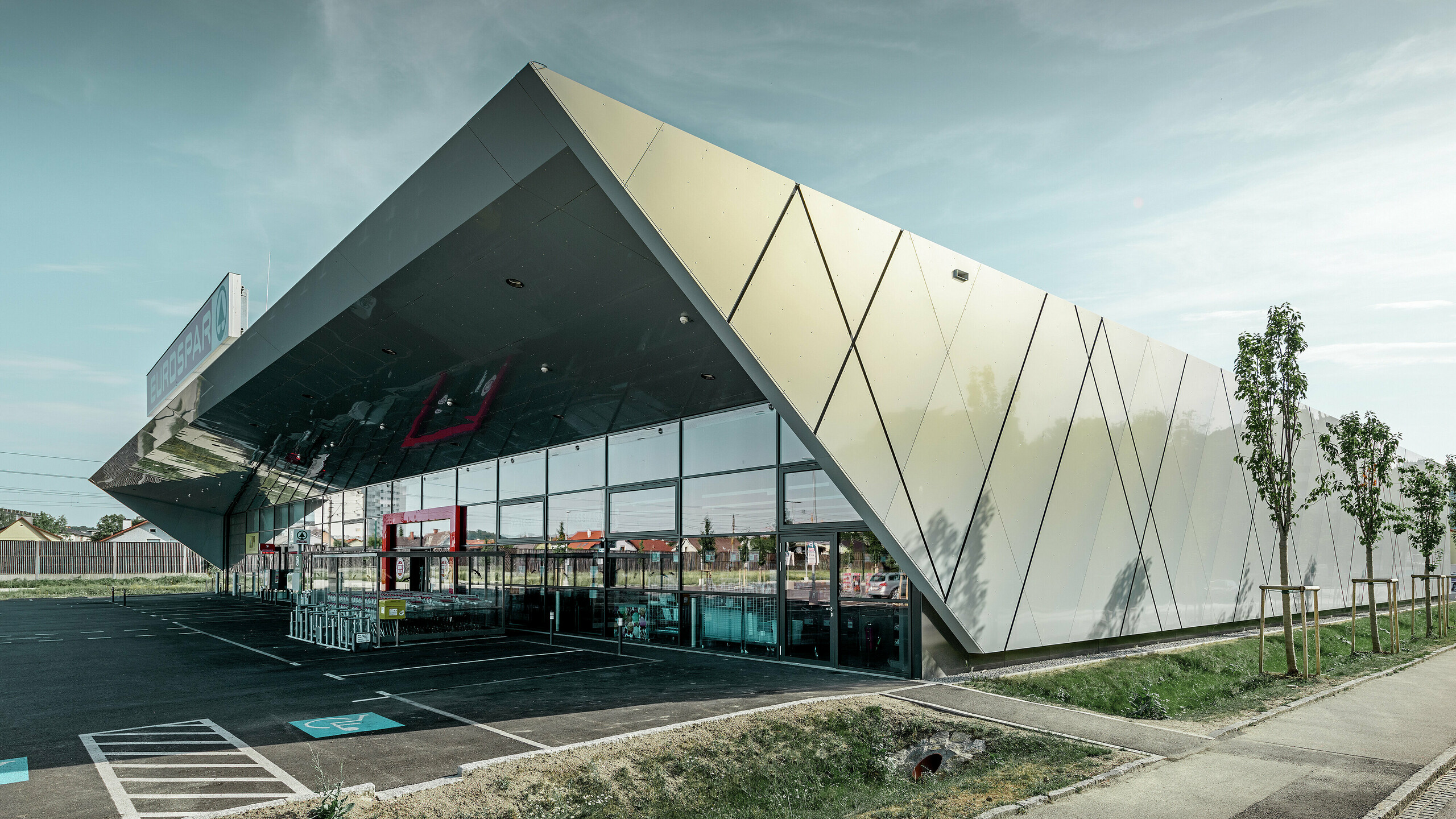 Entrance area of the new Eurospar store in Wels with a modern PREFA façade tile in silver gold. The composite aluminium tiles shimmer in different colours depending on the angle of the sun.