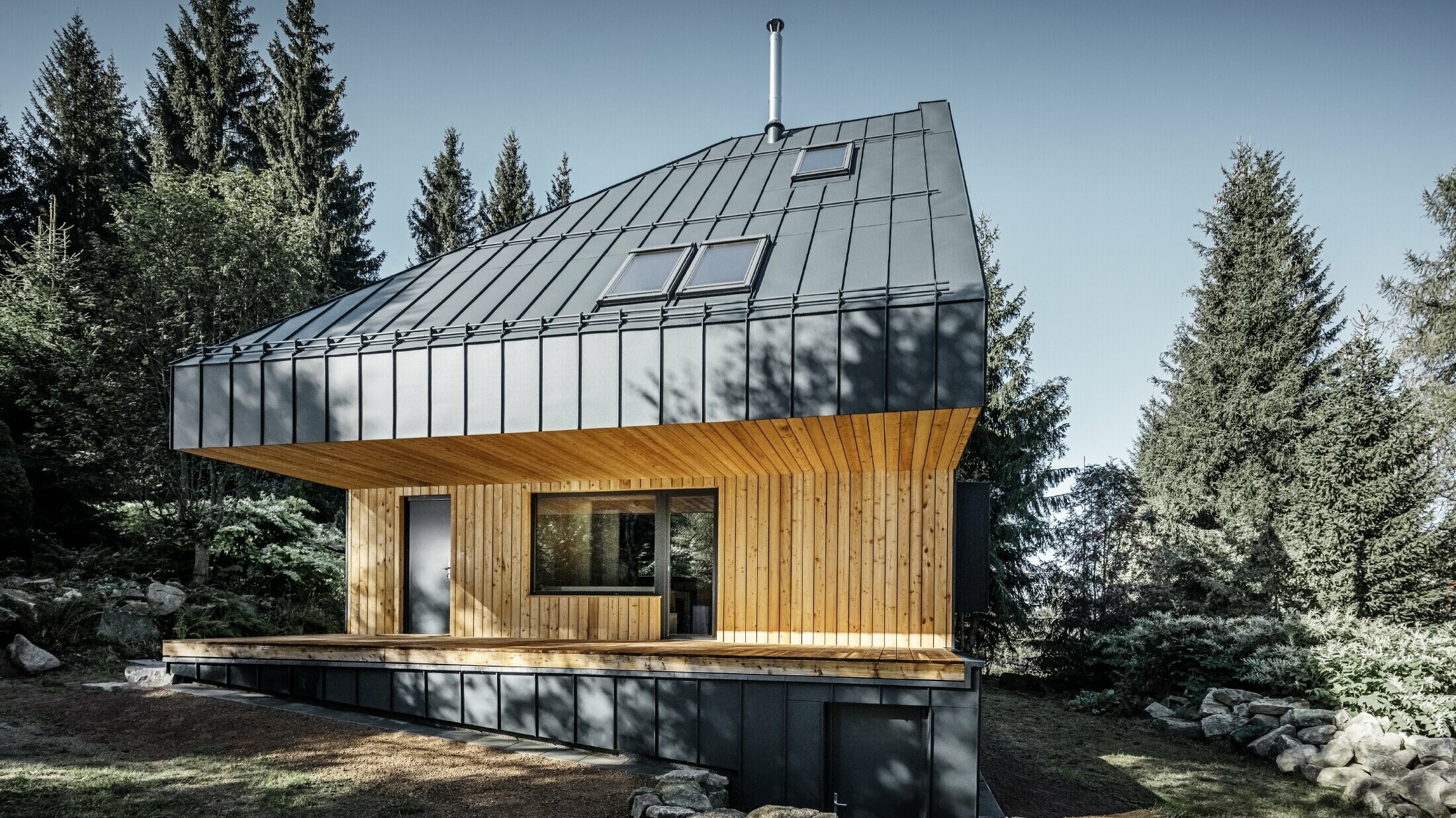 Architecturally designed detached house in the forest, the imposing roof was clad with PREFALZ aluminium from PREFA in anthracite. The soffit and the façade are clad with wooden panels.