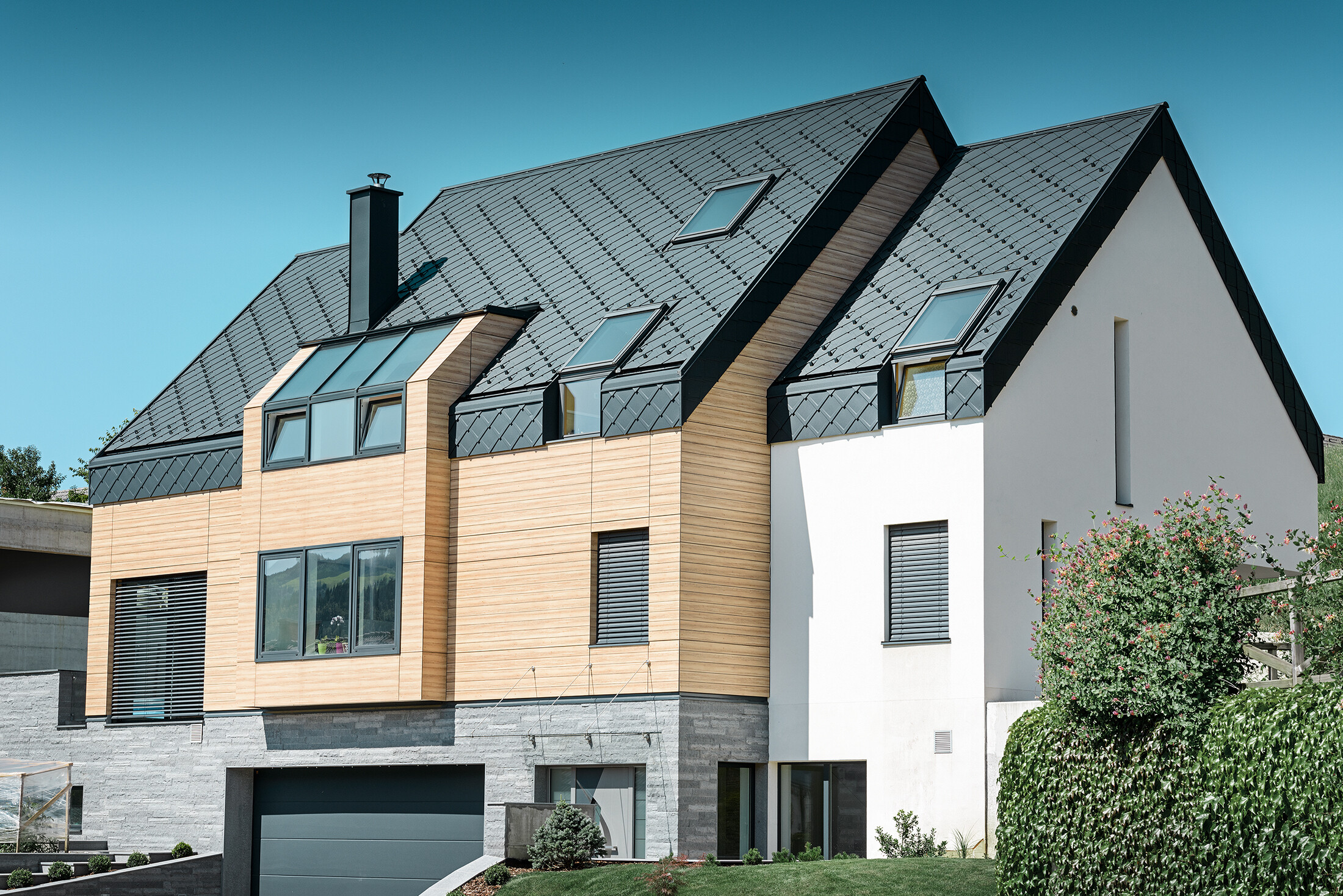 Contemporary new building, where the roof covering also extends over the upper part of the façade, aluminium rhomboid roof tiles in anthracite were used as roof cladding