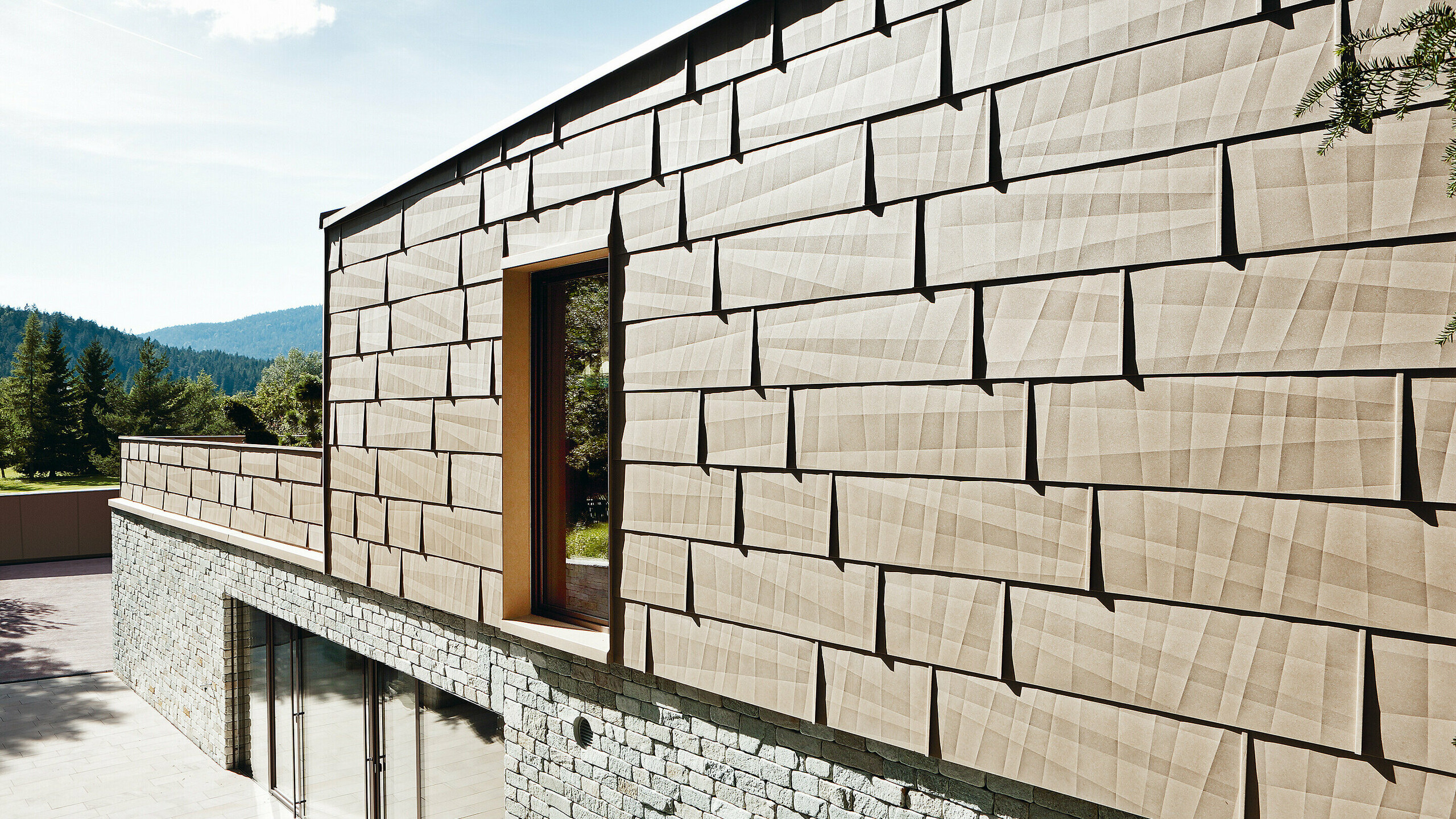 On this external façade, the PREFA FX.12 façade panel in P.10 sand brown has been combined with a stone façade on the bottom floor.