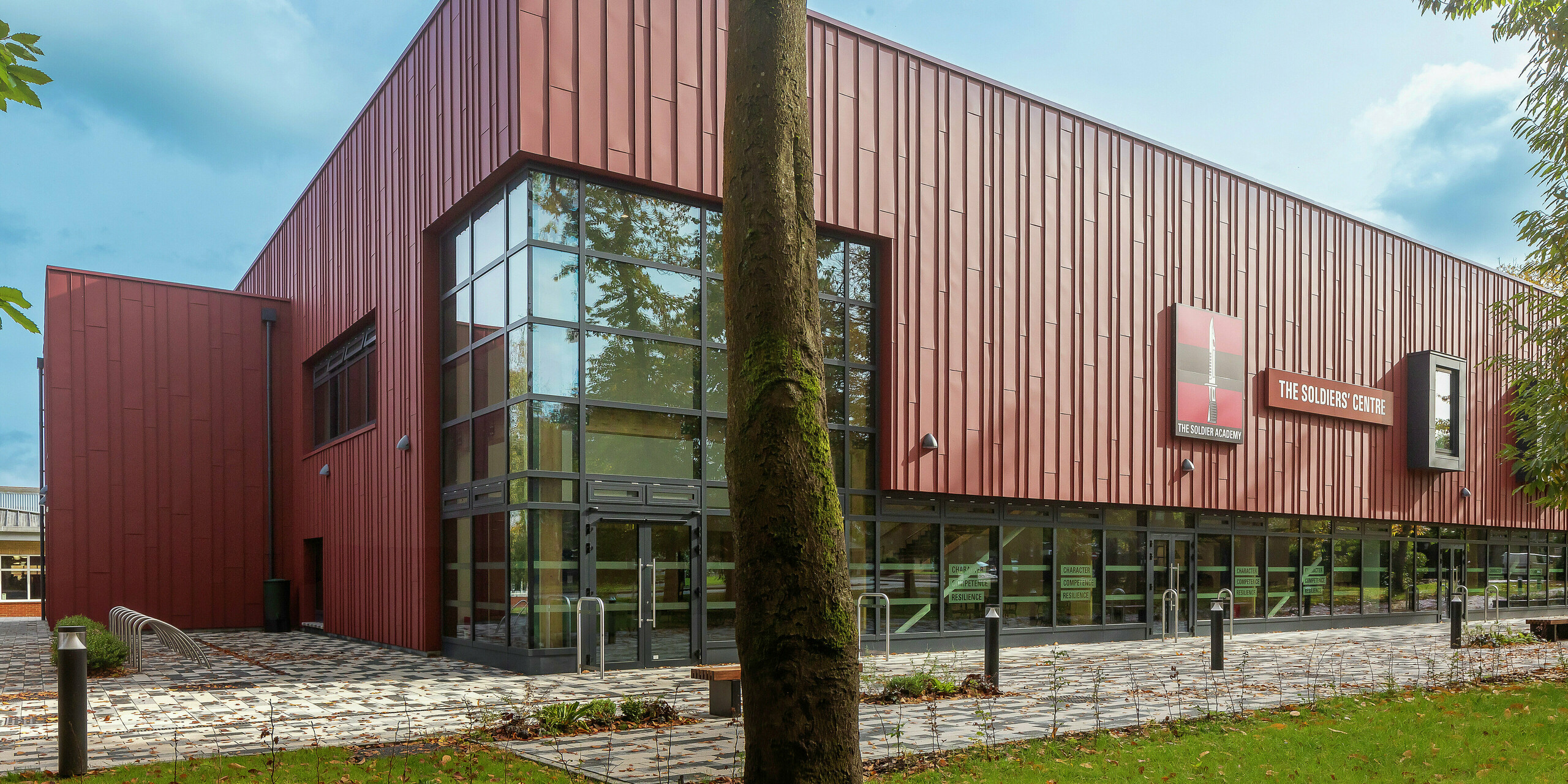 Innovative façade design with PREFALZ: The Soldiers' Centre in Pirbright impresses with modern standing seam cladding made of PREFALZ in P.10 oxide red. Generous glass surfaces ensure a bright, inviting atmosphere, while window frames in P.10 anthracite set stylish accents. Sustainability, durability and design combined – high-quality PREFA aluminium products for future-oriented architecture.
