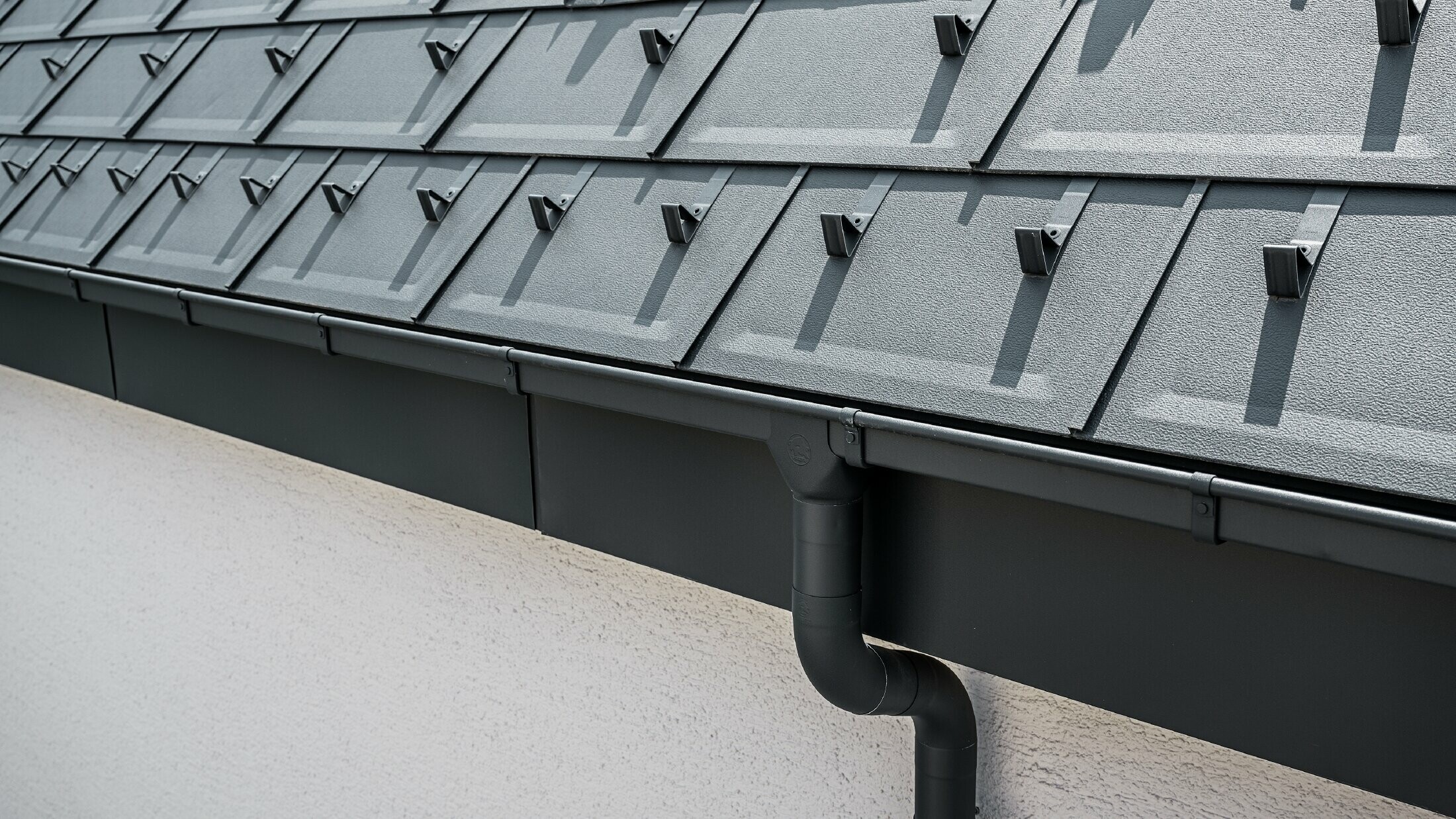 Steep roof surface covered with the roof tile R.16 with square PREFA box gutter with gutter outlet and downpipe in anthracite