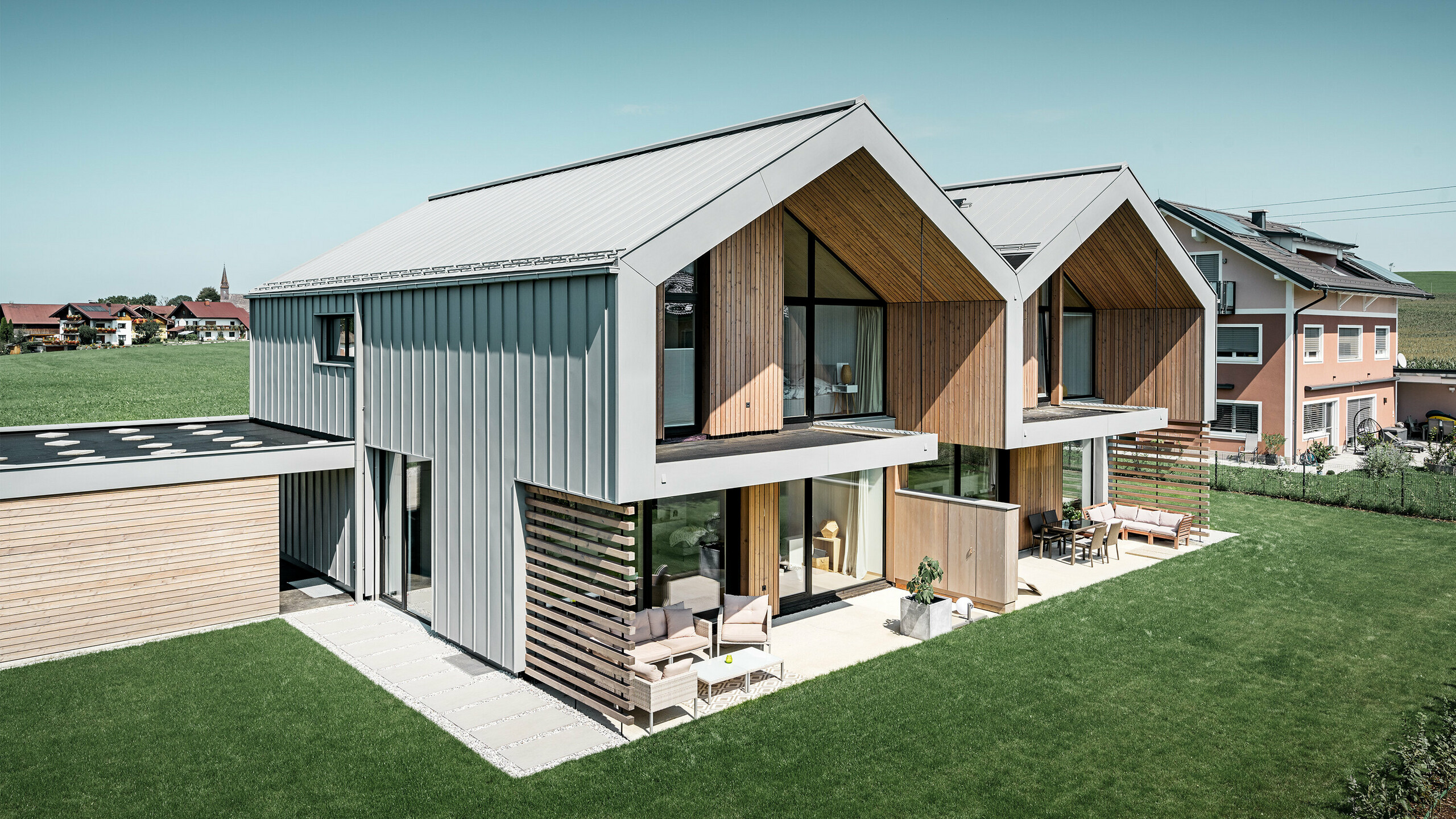 Modern semi-detached houses with PREFALZ (standing seam) building shell, roof and façade are clad with PREFALZ standing seam in patina grey incl. square downpipe