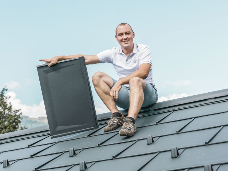 Ein Handwerker sitzt auf einem PREFA Aluminiumdach.